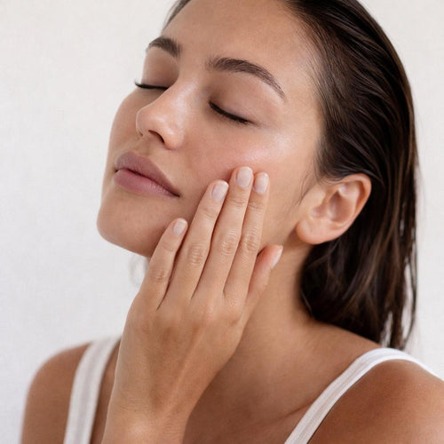 Woman with clear glowing skin touching her face after using a clean face towel